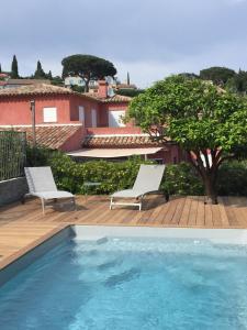 una piscina con 2 sillas y una casa en Villa Heliomar, en Cavalaire-sur-Mer