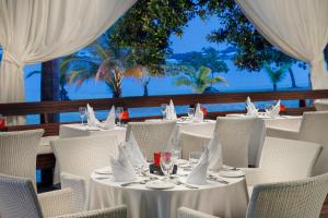 een restaurant met witte tafels en stoelen en de oceaan bij Couples Negril in Negril