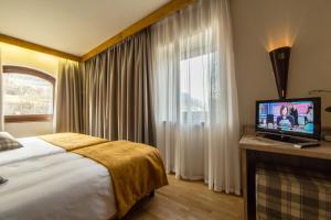 una camera d'albergo con letto e TV di Hotel Comtes De Challant Albergo Etico Valle d'Aosta a Fenis