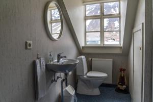 un bagno con lavandino, water e specchio di Guesthouse Gamla a Ísafjörður Altre 24 foto