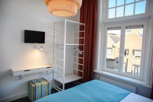 a bedroom with a bed and a desk and a window at Hotel XL in Zandvoort