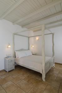 a bedroom with a white canopy bed and a table at Hotel Katerina in Mylopotas
