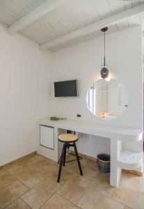 a white kitchen with a table and a stool at Hotel Katerina in Mylopotas