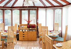 a dining room with tables and chairs and windows at Pymgate Lodge Hotel Manchester Airport in Cheadle