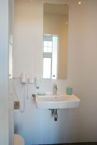 ein weißes Badezimmer mit einem Waschbecken und einem Spiegel in der Unterkunft Hotel XL in Zandvoort