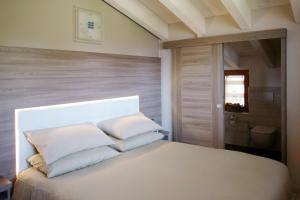 ein Schlafzimmer mit einem weißen Bett mit weißen Kissen in der Unterkunft Agriturismo Ruc del Lac in Boario Terme