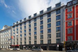 un grand bâtiment avec des voitures garées devant lui dans l'établissement Aparthotel Adagio Muenchen City, à Munich