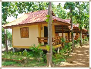 een klein geel huis met een rood dak bij Sakthong Resort in Sawankhalok