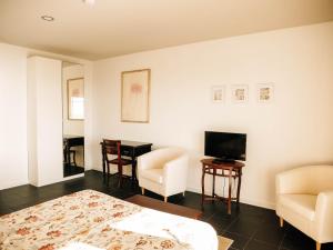 a bedroom with a bed and a television and chairs at Casa das Barcas in Lourinhã
