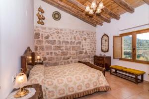 Albergue Casa de l'Aigua في بيسييت: غرفة نوم بسرير وجدار حجري