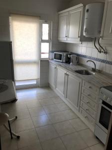 a kitchen with white cabinets and a sink and a window at Edificio Canoa in Armação de Pêra
