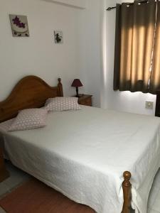una camera da letto con un letto con lenzuola bianche e una finestra di Edificio Canoa ad Armação de Pêra