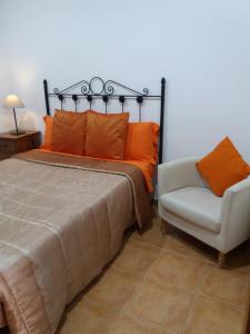 a bedroom with a bed with an orange pillow and a chair at Antequeruela Tourists Home in Toledo