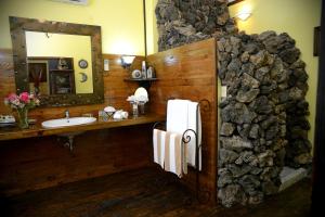 baño con pared de piedra con lavabo y espejo en Posada de las Flores La Paz, en La Paz