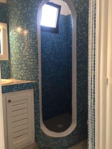 ein Badezimmer mit einem Spiegel und einer blau gefliesten Wand in der Unterkunft Studio Lipstick in Saly Portudal