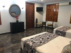 a hotel room with two beds and a mirror at Izamal Plaza in Izamal