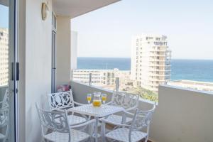 balcón con mesa, sillas y vistas al océano en 43 Sea Lodge - by Stay in Umhlanga en Durban