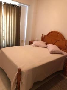 a bedroom with a large bed with white sheets and pink pillows at Edificio Nau in Armação de Pêra