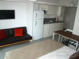a living room with a black couch and a white refrigerator at The Sancy in Rosario