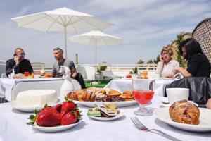 a table with strawberries and croissants and people taking pictures at La Fenice Salentina in Alezio
