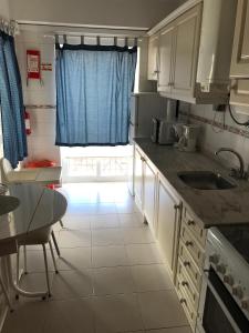 a kitchen with a sink and a table and a window at Caravela B in Armação de Pêra