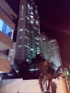 ein hohes Gebäude mit Palmen in einer Stadt in der Nacht in der Unterkunft Habitación I frente a la playa ( Bocagrande ) in Cartagena de Indias