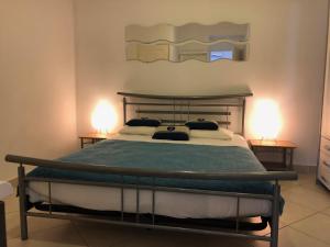 - une chambre avec un grand lit et deux lampes dans l'établissement La Résidence du Cap, au Lavandou