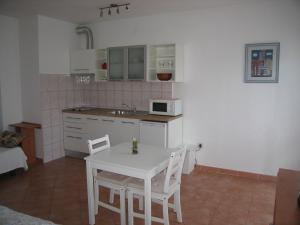 una pequeña cocina con mesa blanca y sillas en Studio Max with parking, en Rovinj