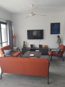 ein Wohnzimmer mit einem Sofa, Stühlen und einem TV in der Unterkunft Studio Sunshine in Saly Portudal
