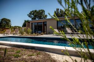 a swimming pool with chairs and a house at Pestana Troia Eco-Resort & Residences in Troia