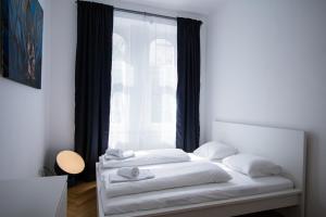 Schlafzimmer mit einem Bett mit weißer Bettwäsche und einem Fenster in der Unterkunft Porzellangarten Apartment I contactless Check-In in Wien