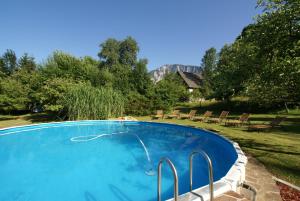a swimming pool with chairs and a mountain in the background at Gasthof Hotel Zur Post in Ferlach