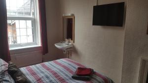 a bedroom with a bed and a sink and a window at Angel Guesthouse in Tiverton