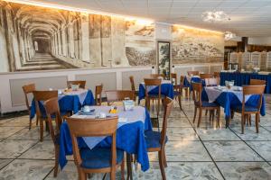 a dining room with tables and chairs and a painting at Hotel Ariston in Imperia