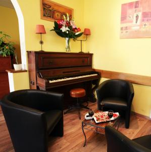 a living room with a piano and two chairs at Hôtel Des Nacres in Ventiseri