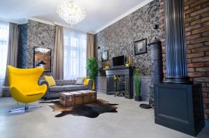 a living room with a yellow chair and a brick wall at Viktoria Luxury Apartment in Budapest