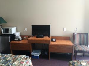 a desk in a hotel room with a computer on it at Aries Motel in Edson