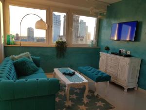 sala de estar con sofá azul y TV en Centre Apartamenty Warszawa, en Varsovia