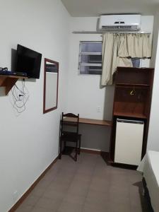 Cette chambre comprend un bureau, une télévision et une chaise. dans l'établissement Hotel Danubio, à Itabaiana