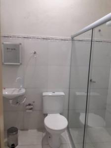 a white bathroom with a toilet and a sink at Hotel Danubio in Itabaiana