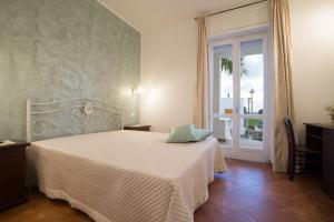 una camera da letto con un letto bianco e una finestra di CORTE DELL'IMMACOLATA AL MARE a Marina di Mancaversa