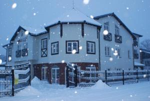 ein schneebedecktes Haus vor einem Zaun in der Unterkunft Amigo Hotel in Sulejówek