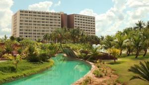 um resort com piscina, palmeiras e edifícios em Hot Beach Resort em Olímpia