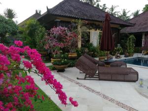甘地達薩的住宿－鳳梨別墅，庭院设有两把椅子和一把遮阳伞,鲜花盛开