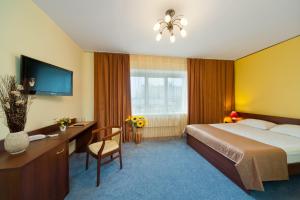 a hotel room with a bed and a desk and a television at Hotel Ukraina in Voronezh
