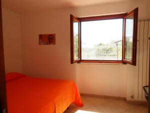 スカウリにあるVilla Ginaのベッドルーム1室(オレンジ色のベッド1台、窓付)