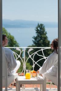 two people sitting on a porch with oranges on a table at BRISTOL Hotel Opatija in Opatija