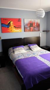 a bedroom with a purple bed with paintings on the wall at Welcome to Santiago - Chile in Santiago