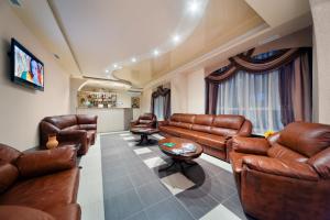 a living room with leather furniture and a flat screen tv at Hotel Ukraina in Voronezh