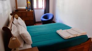 een slaapkamer met een blauw bed en een blauwe stoel bij Apartamento Tavira in Tavira